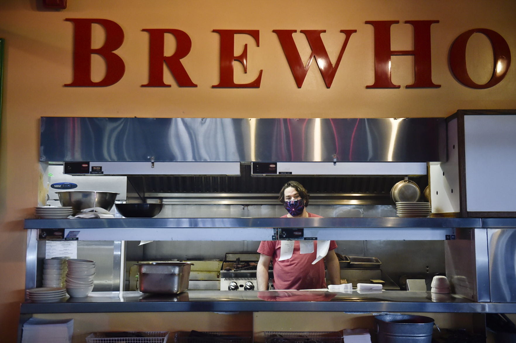 A cook at Brewhouse Pub and Grille checks on a food order